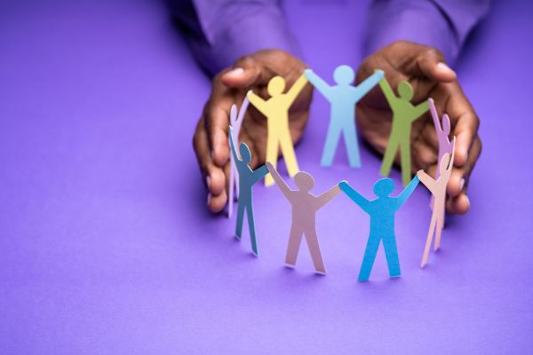 image of pair of hands holding a circle of paper people in various colours