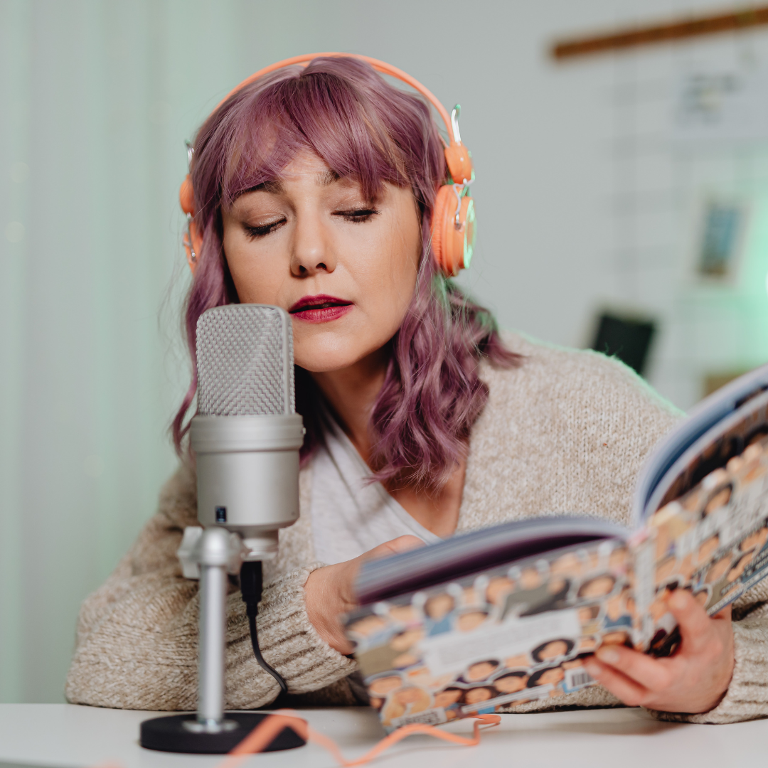 woman talking into a microphone and reading aloud from a book