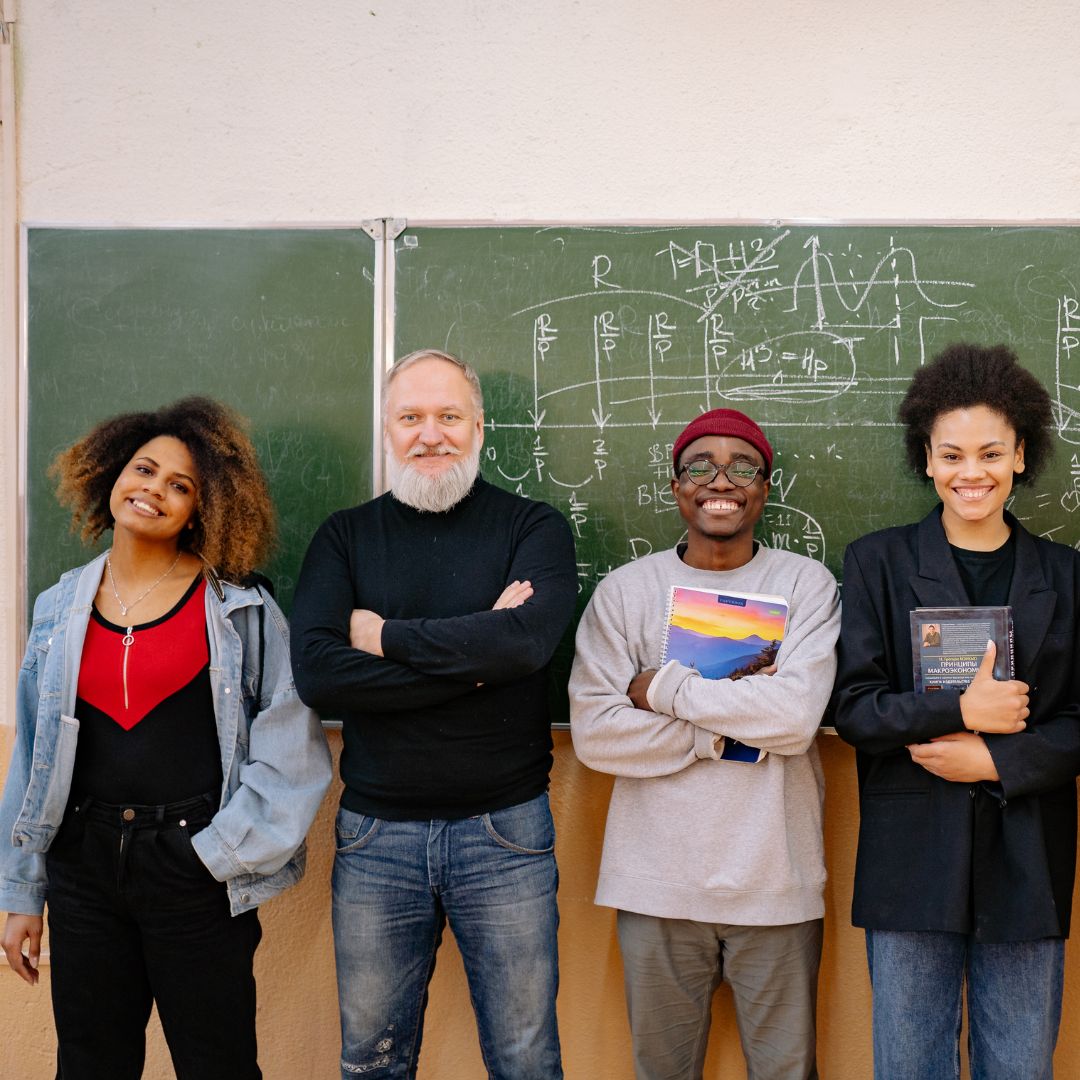 Image of four people stood with backs against chalk board