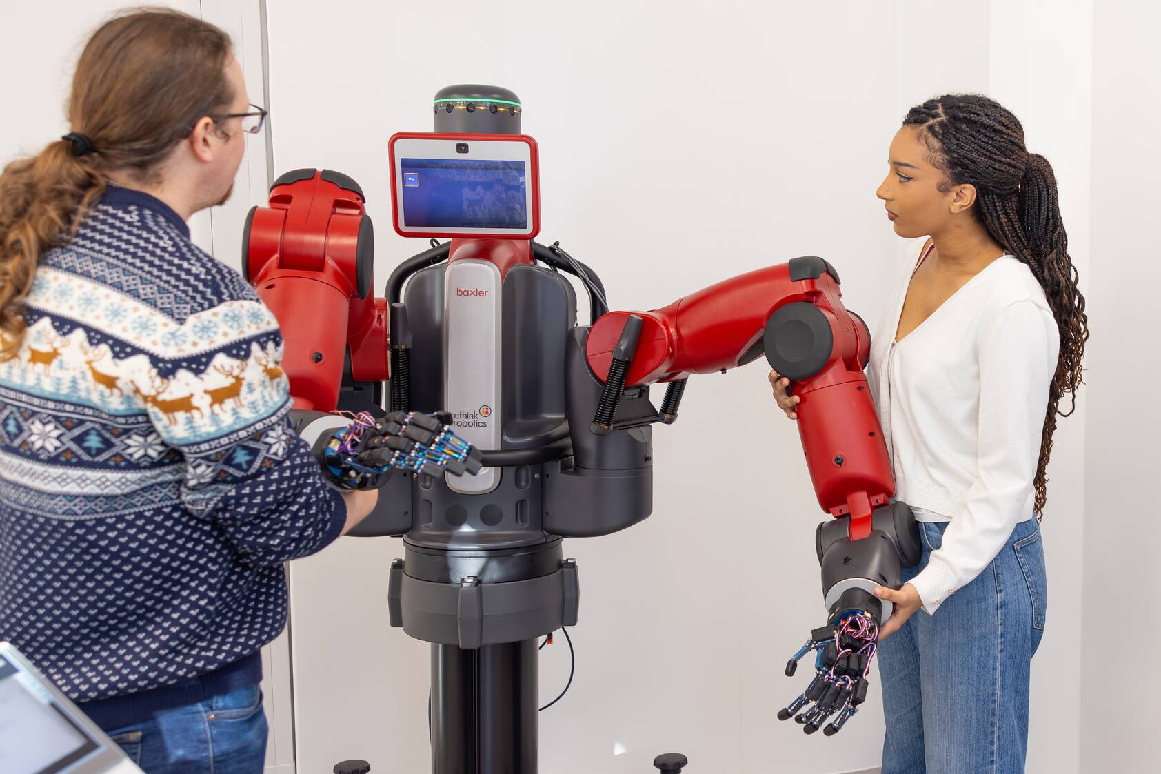Image shows 2 people holding robotic arms attached to an ipad and stand.