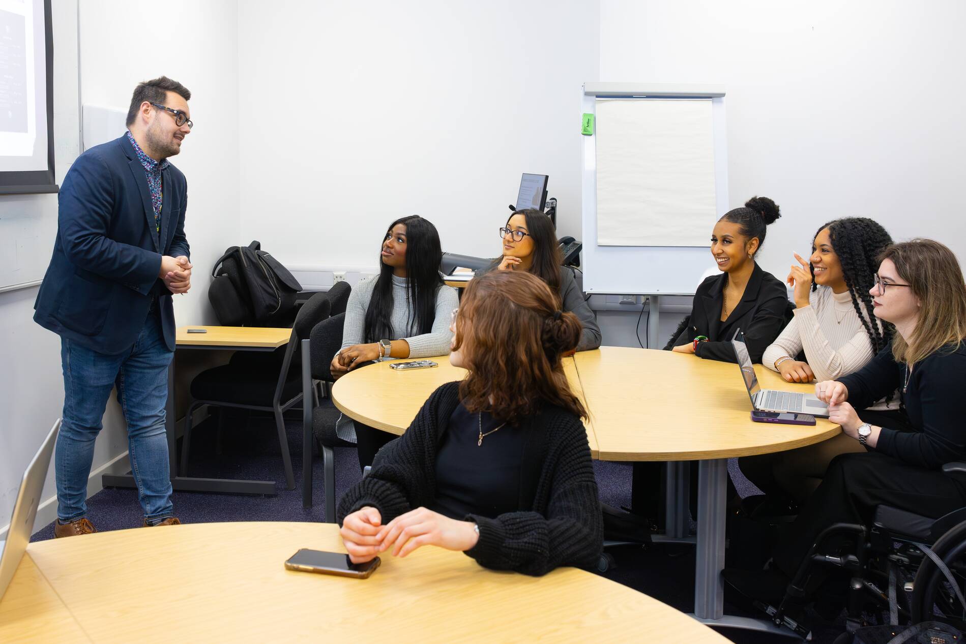 Image of people sat round a table listening to an academic.