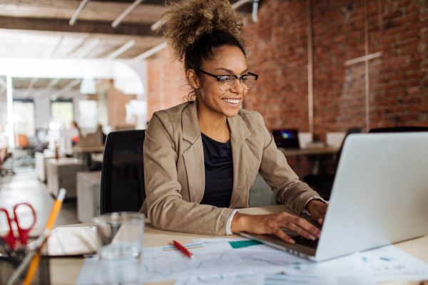 Image of woman sat at desk working on her laptop