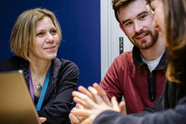 image of 3 people sat around a laptop in discussion