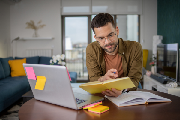 image of a man on a laptop looking at books and resources