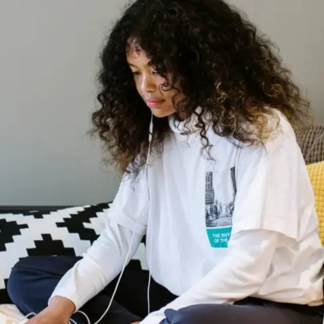 Image of student sat on bed listening to music