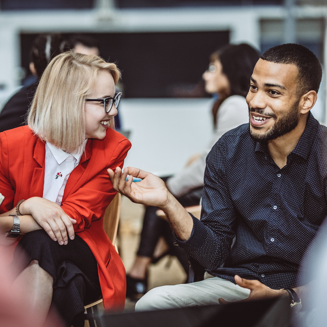 Image of two colleagues sat down and in conversation, both are smiling