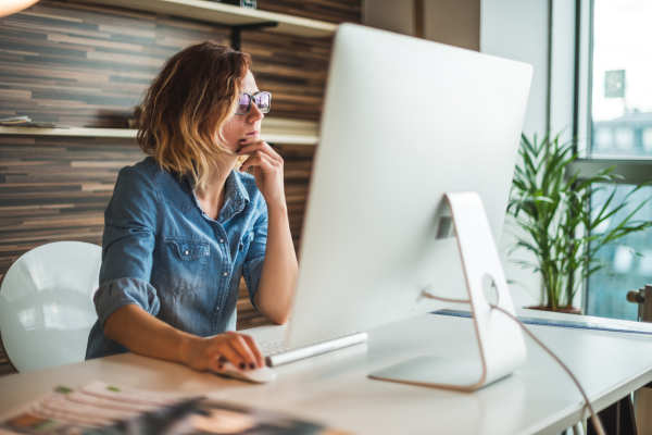 Image of woman sat at desk using her computer for research