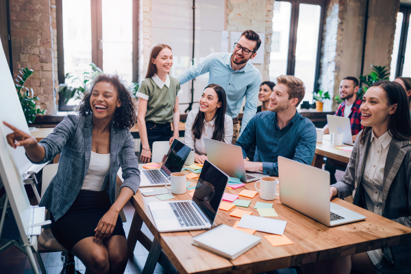 Image of people sat with laptops and flip chart in discussion and collaborating