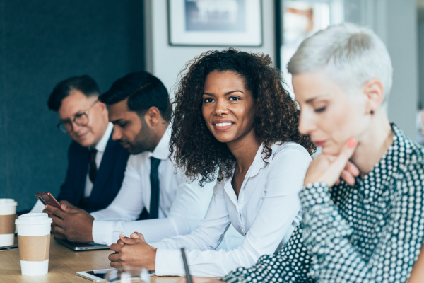 Image of people sat at a table, one looking directly at camera