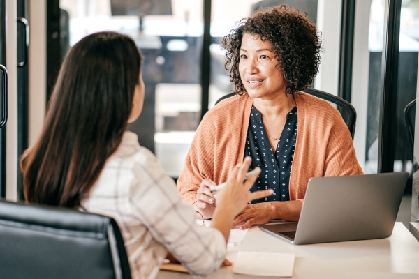 Image of two women sat at desk in conversation