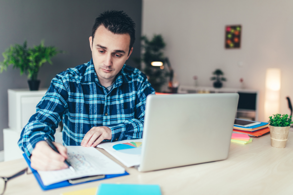 male student sat at desk with laptop studying
