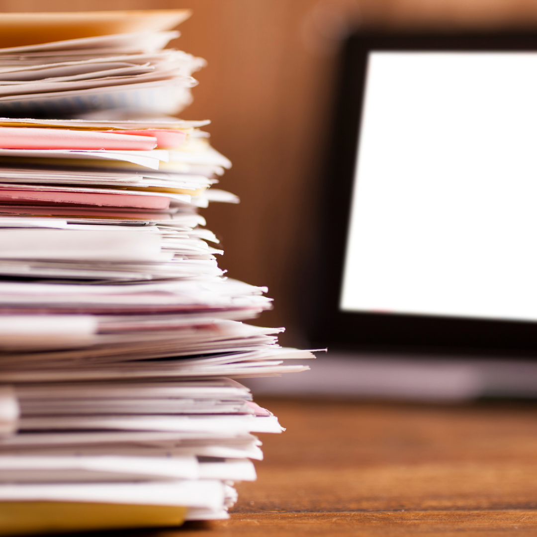 image of pile of files next to a laptop