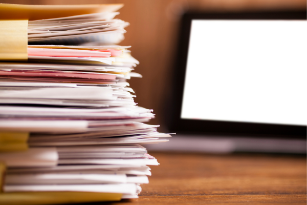 image of pile of files next to a laptop