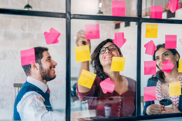 Image of people adding post-it notes to a clear board