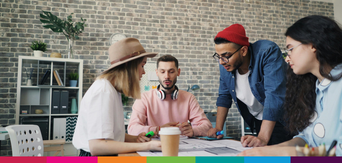 Image of four students collaborating and planning around a desk