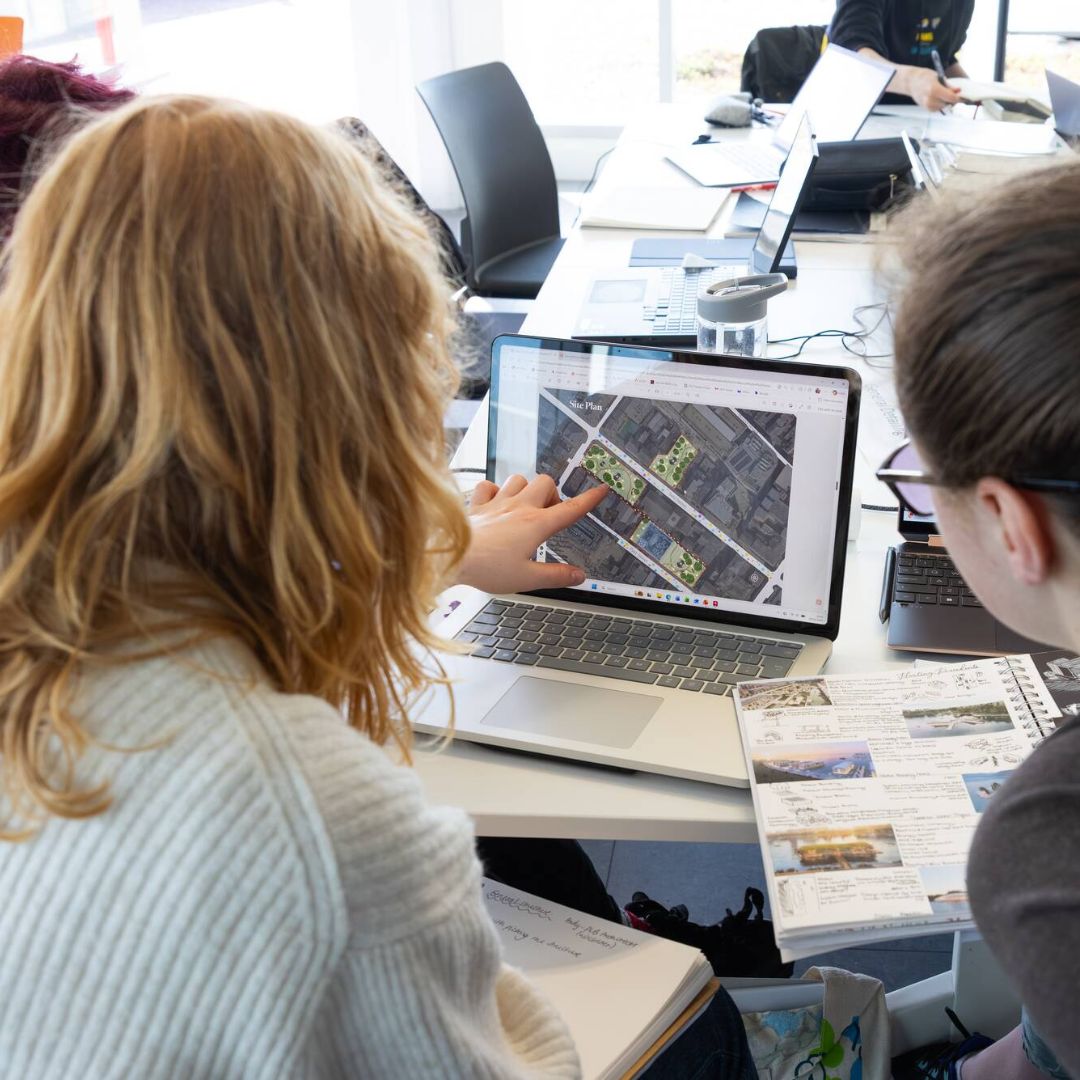 Image shows students looking at an image on a laptop.