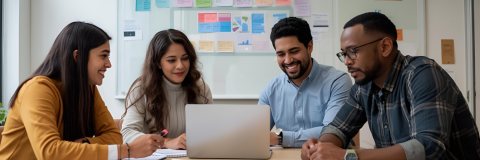 Image of people sat round looking at a laptop